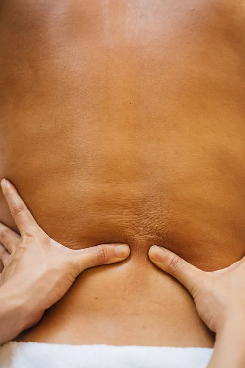 Hands applying focused pressure to a person's back